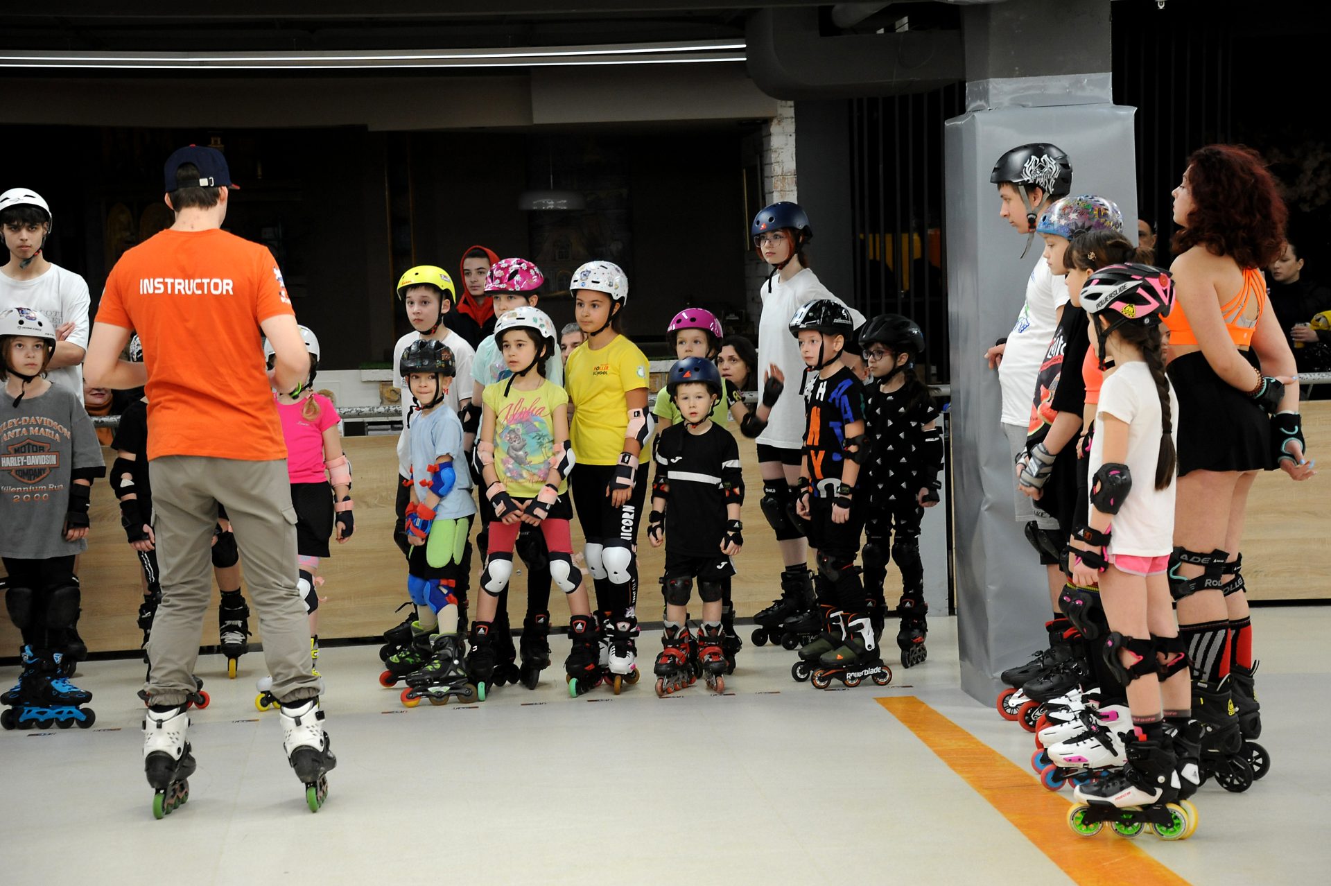 Instructor Roller Park explicând exercițiul unui grup de copii echipați cu role