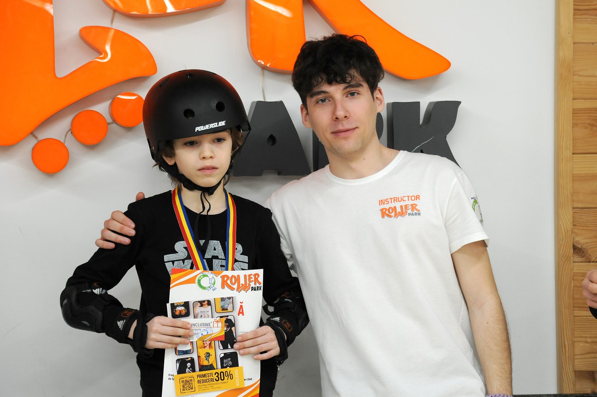 Copil cu medalie și diplomă alături de instructorul Roller Park Chișinău